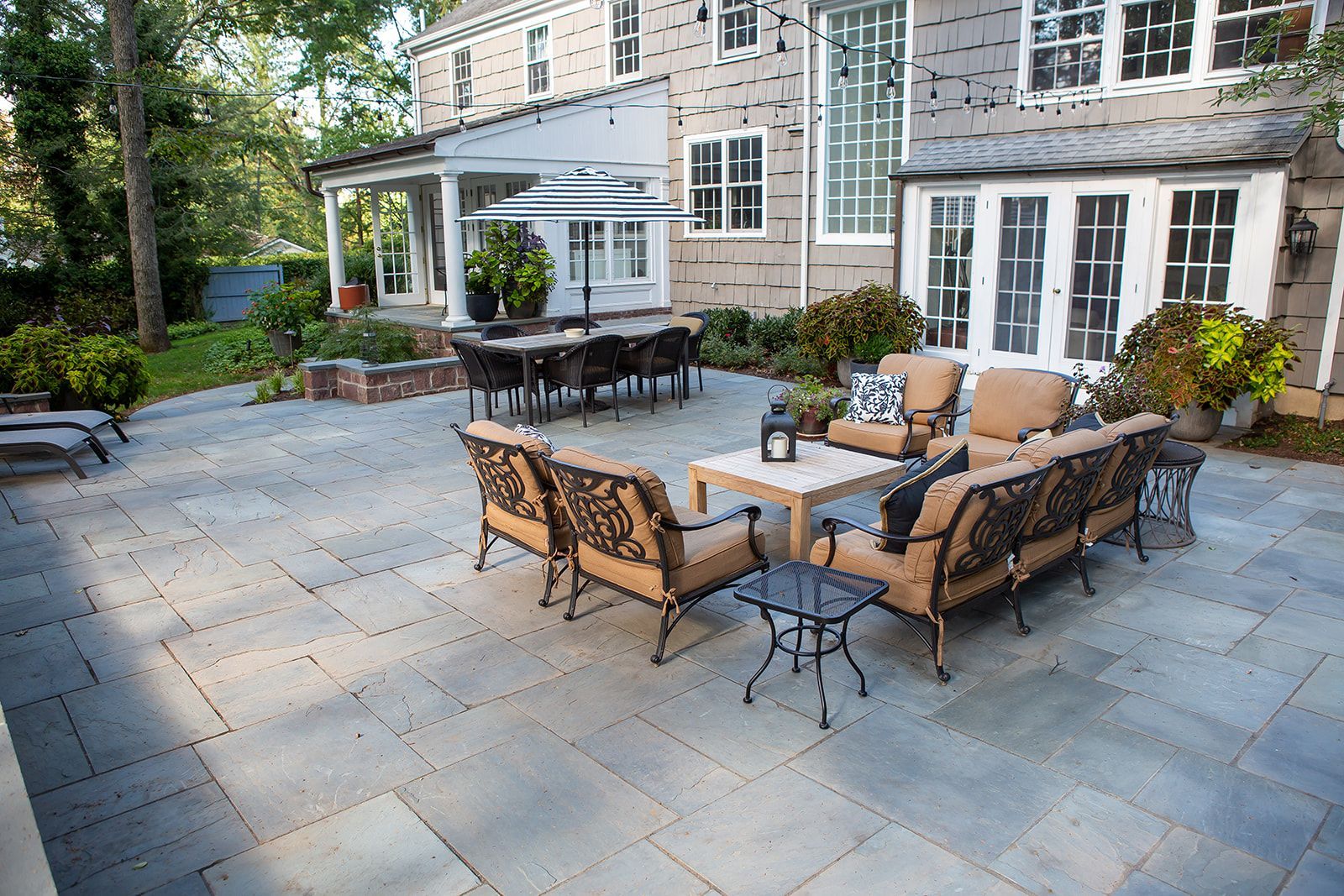 A large patio with a lot of furniture in front of a house.