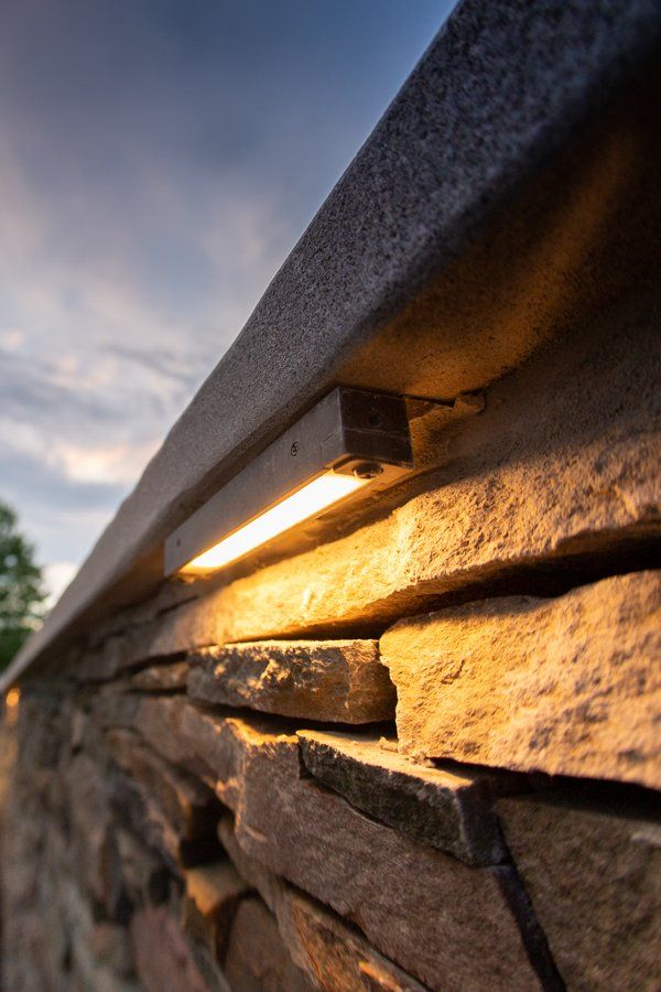 Stone wall with warm lighting, highlighting the texture, and a twilight sky in the background.