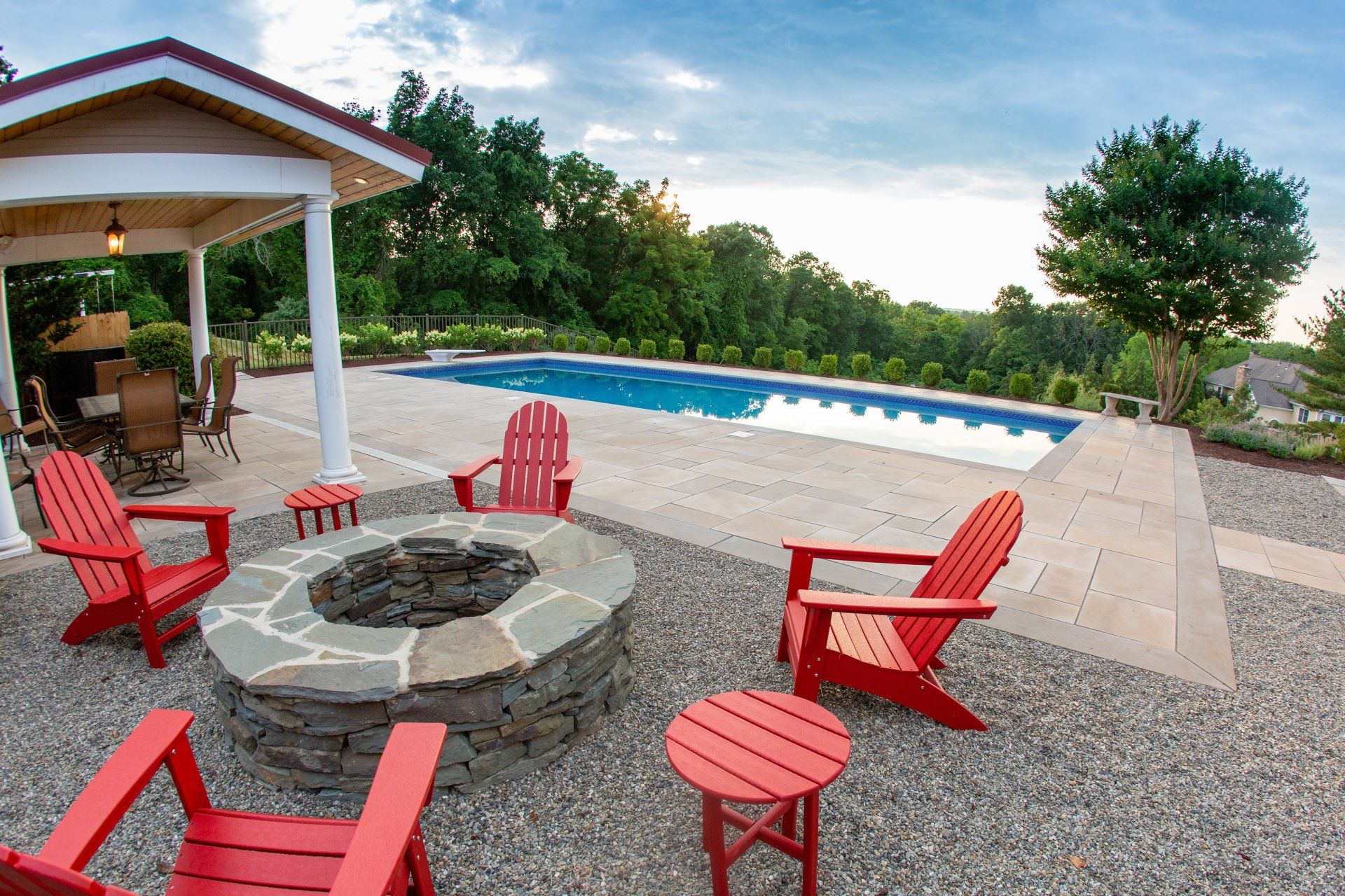 Outdoor patio with pool, fire pit, red chairs, and a gazebo.