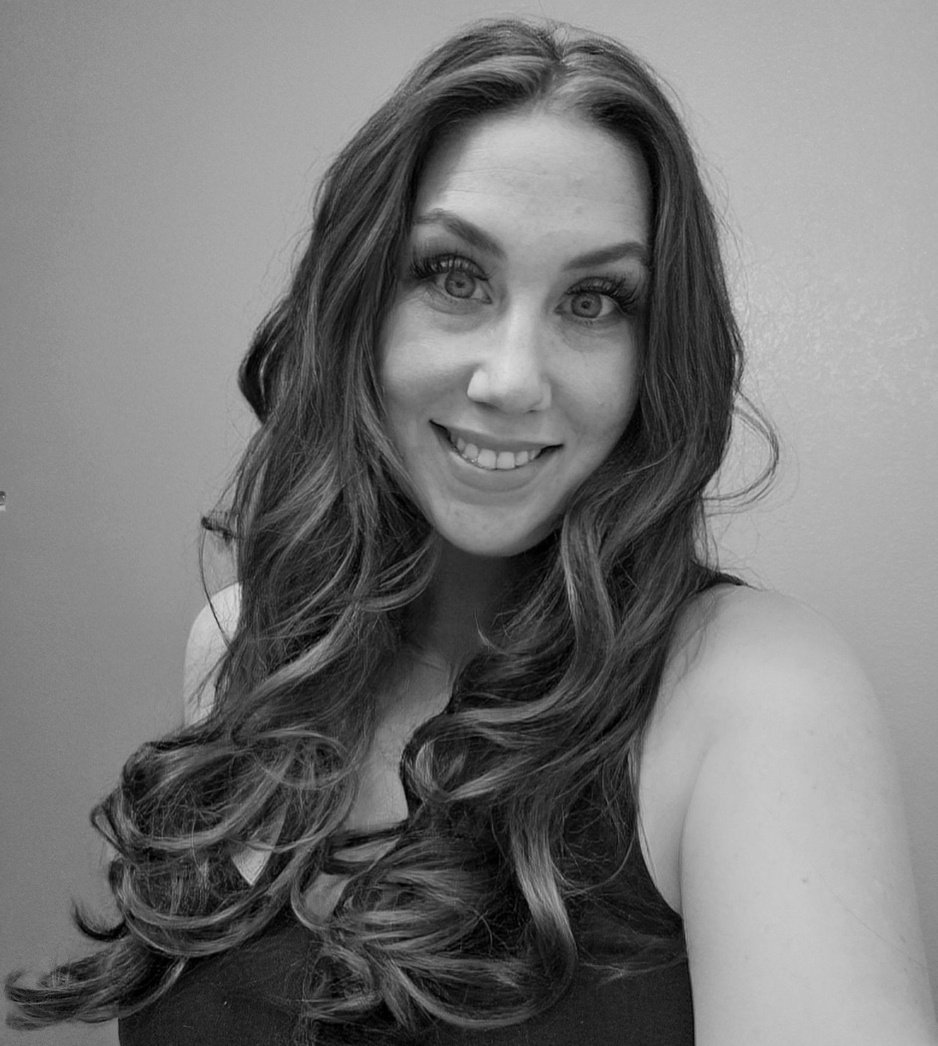 A woman with long hair is smiling in a black and white photo.