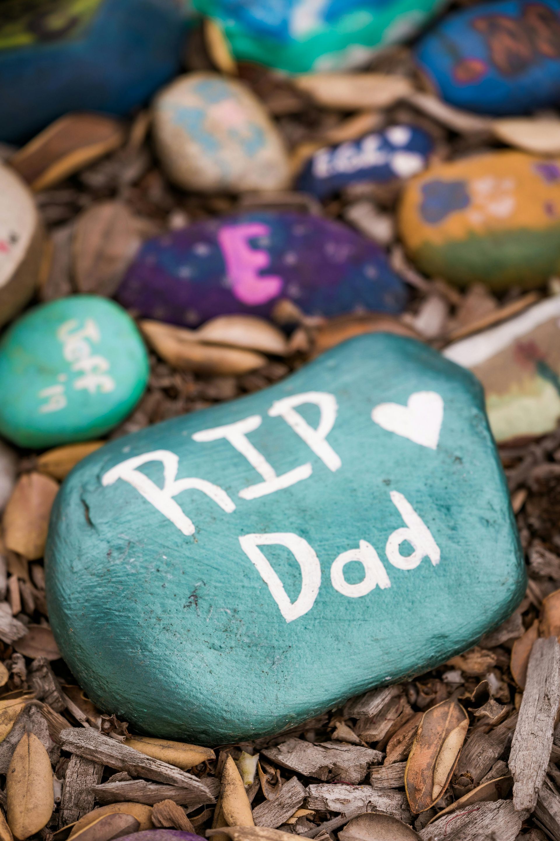 A blue rock with the words rip dad written on it