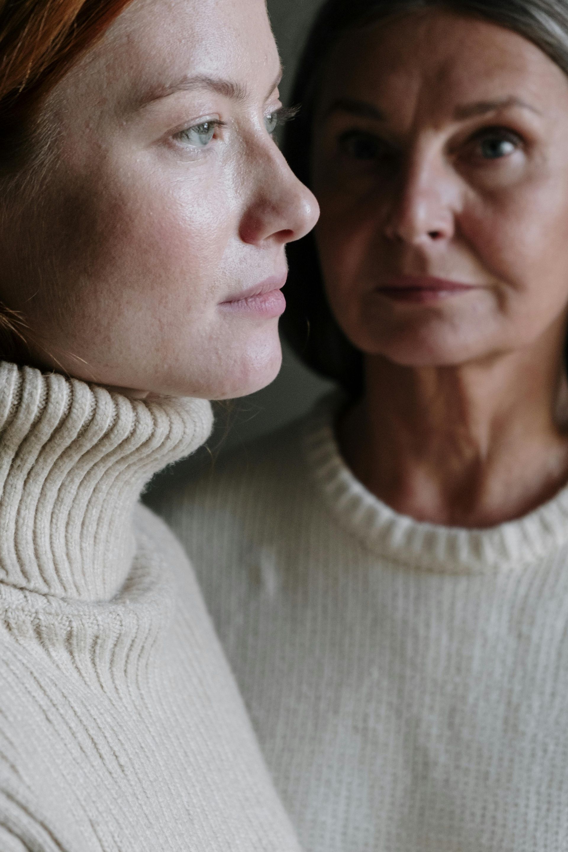 Two women in white sweaters are looking at each other.