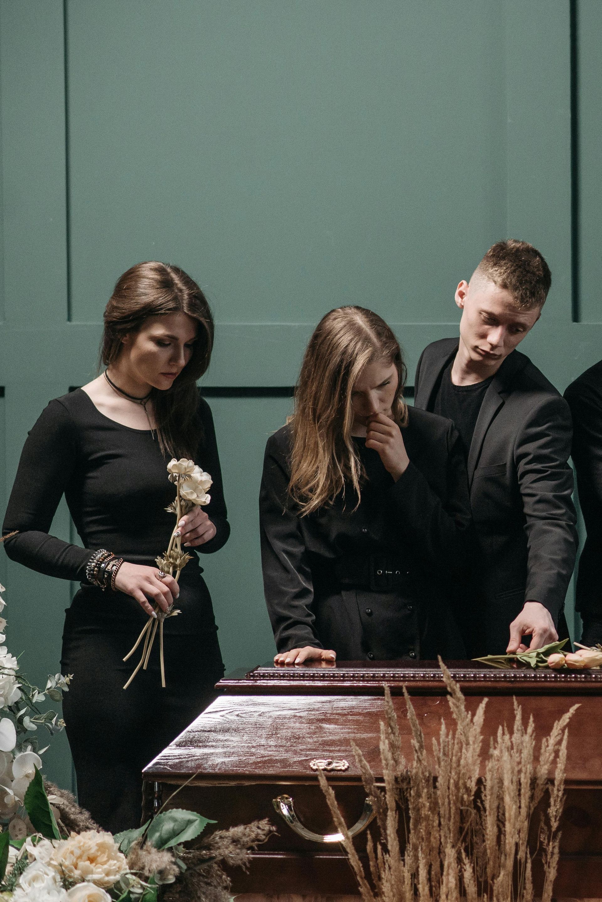 A group of people are standing around a coffin at a funeral.