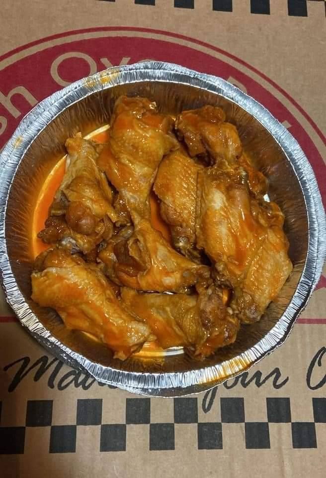 Aluminum foil container filled with chicken wings on a pizza box