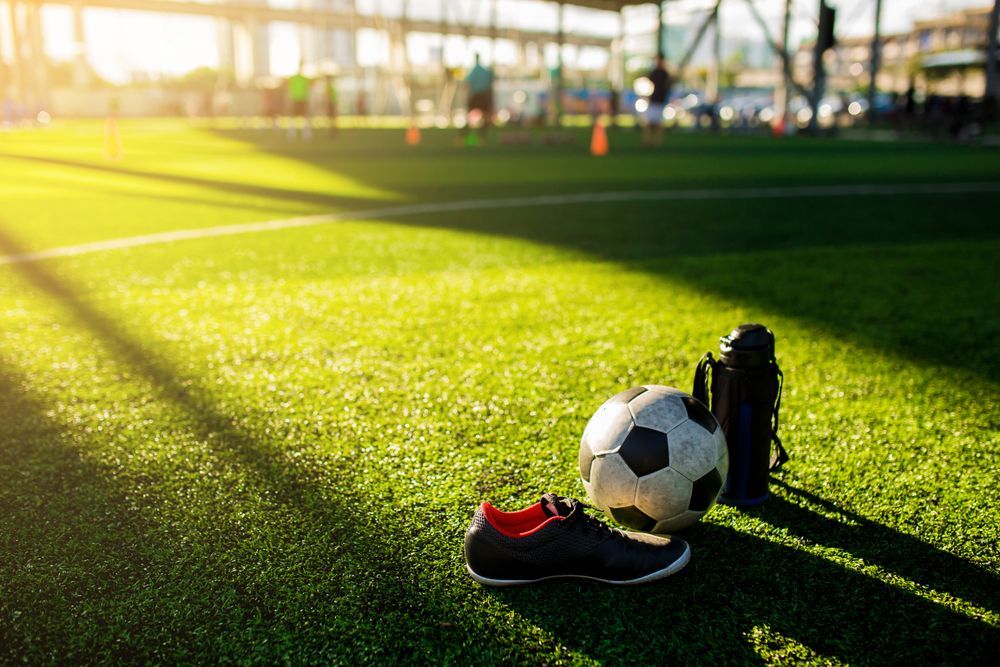 Soccer Ball, Shoe, and Water Bottle on A Green Turf Field — East Coast Hydroseeding in Cooperabung, NSW