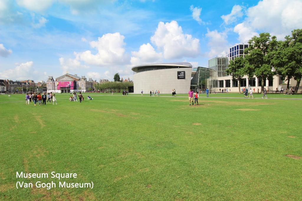 Eine Gruppe von Menschen steht auf einer Wiese vor dem Van Gogh Museum