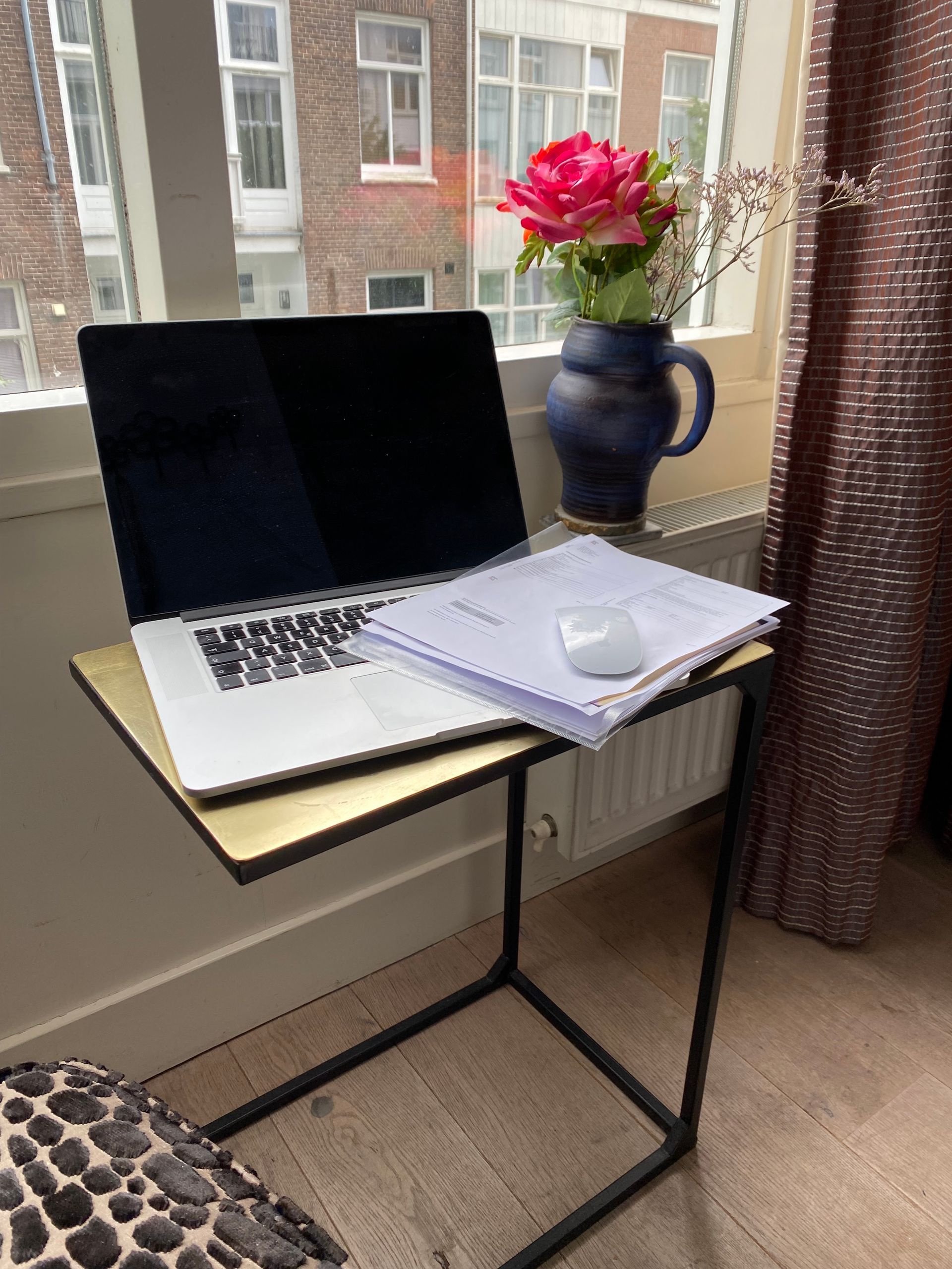 Ein Laptop steht auf einem Tisch neben einer Blumenvase