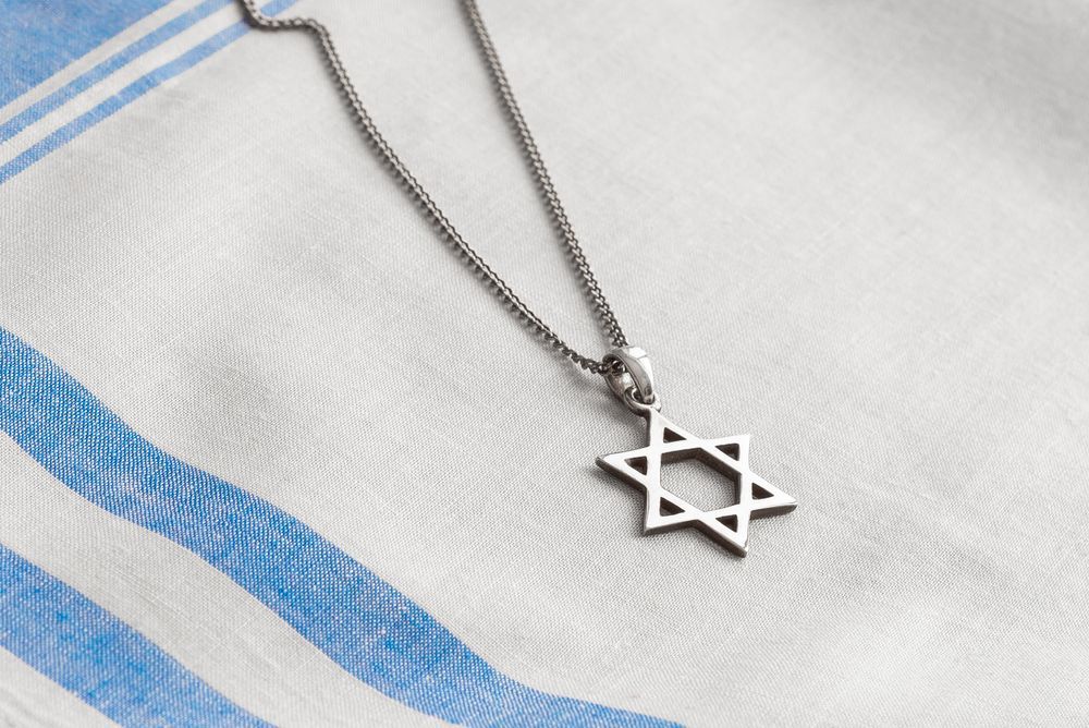 Silver Star of David necklace on a white and blue striped cloth.