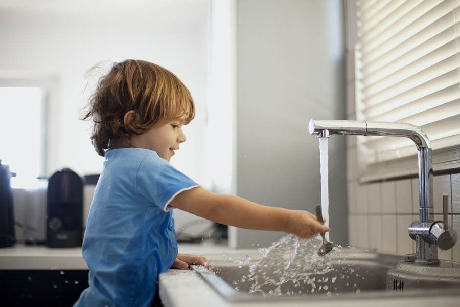Bambino al rubinetto della cucina