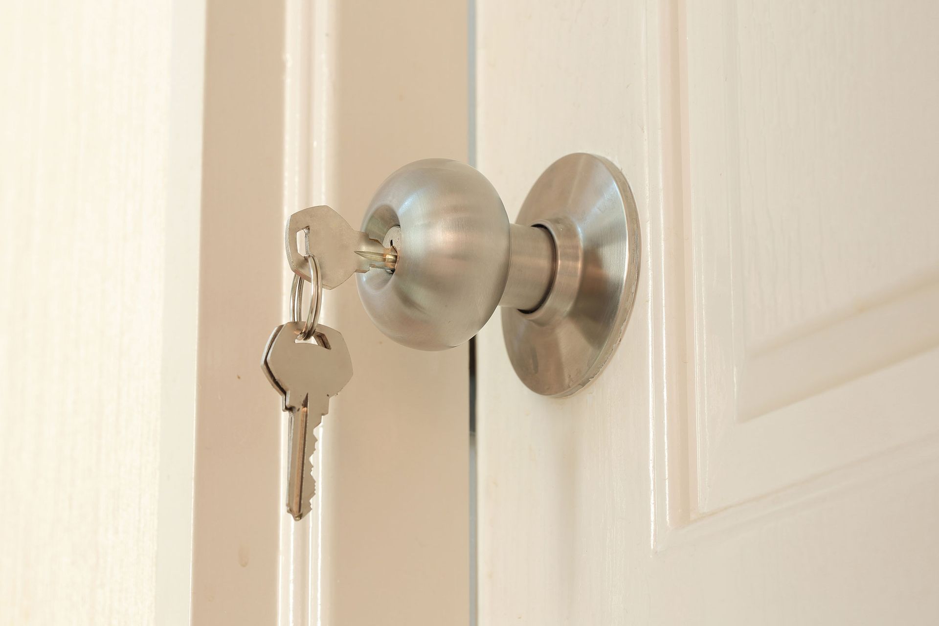A close up of a door knob with two keys in it.