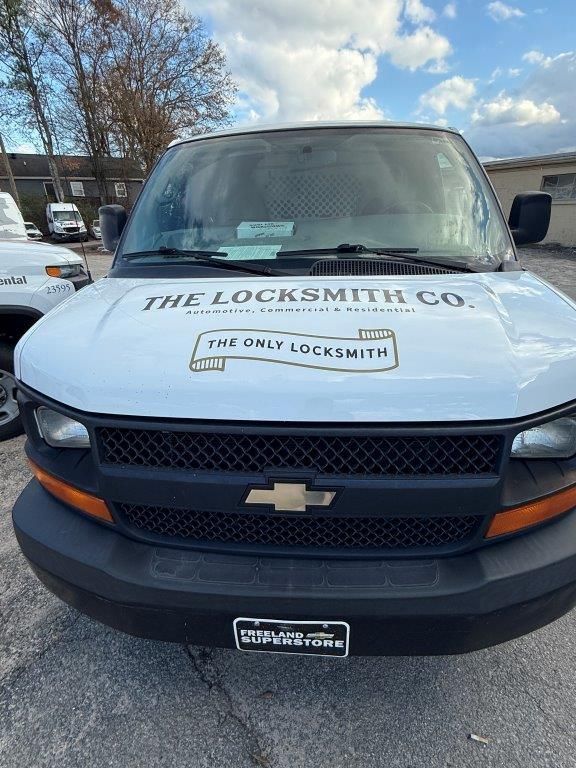 A white van with the word locksmith on the hood is parked in a parking lot.