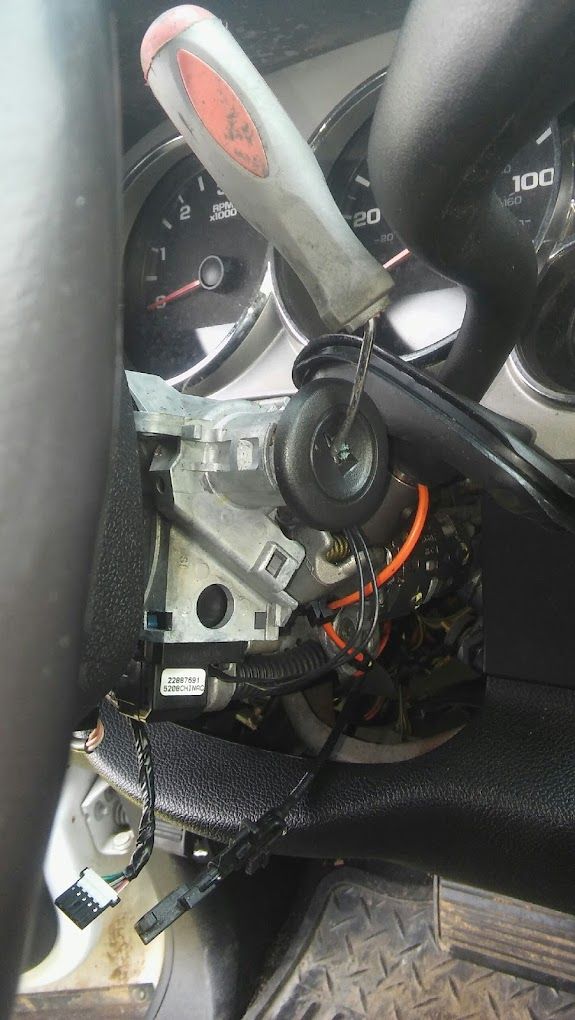 A person is holding a screwdriver next to a steering wheel in a car.