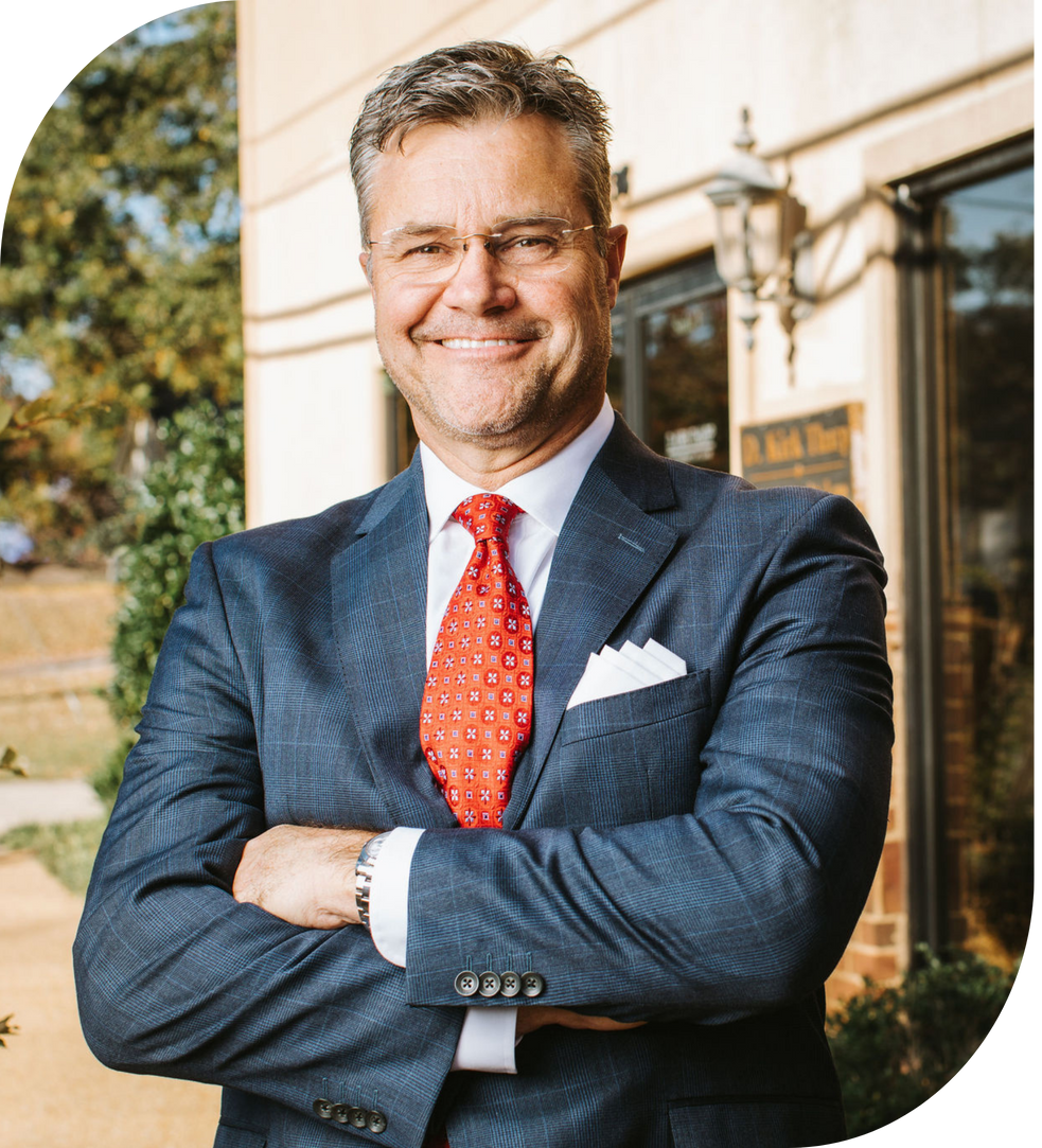 A man in a suit and tie is standing in a room with his hands in his pockets.