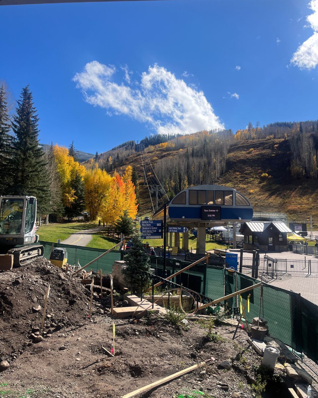 Mountain ski lift amidst autumn foliage. Construction in foreground. Sunny, blue sky.