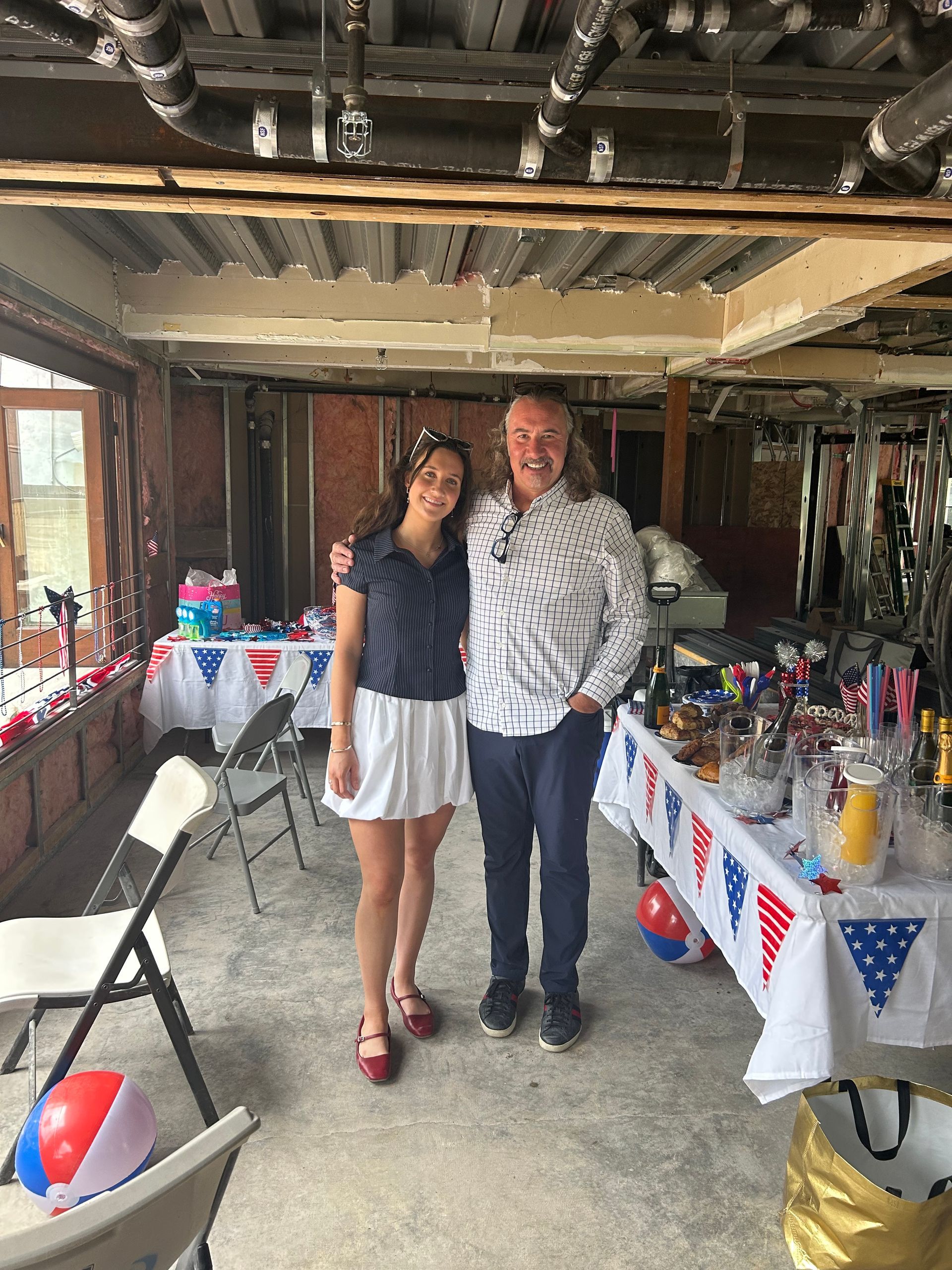 A young woman and man pose together in a decorated, open-air space. 