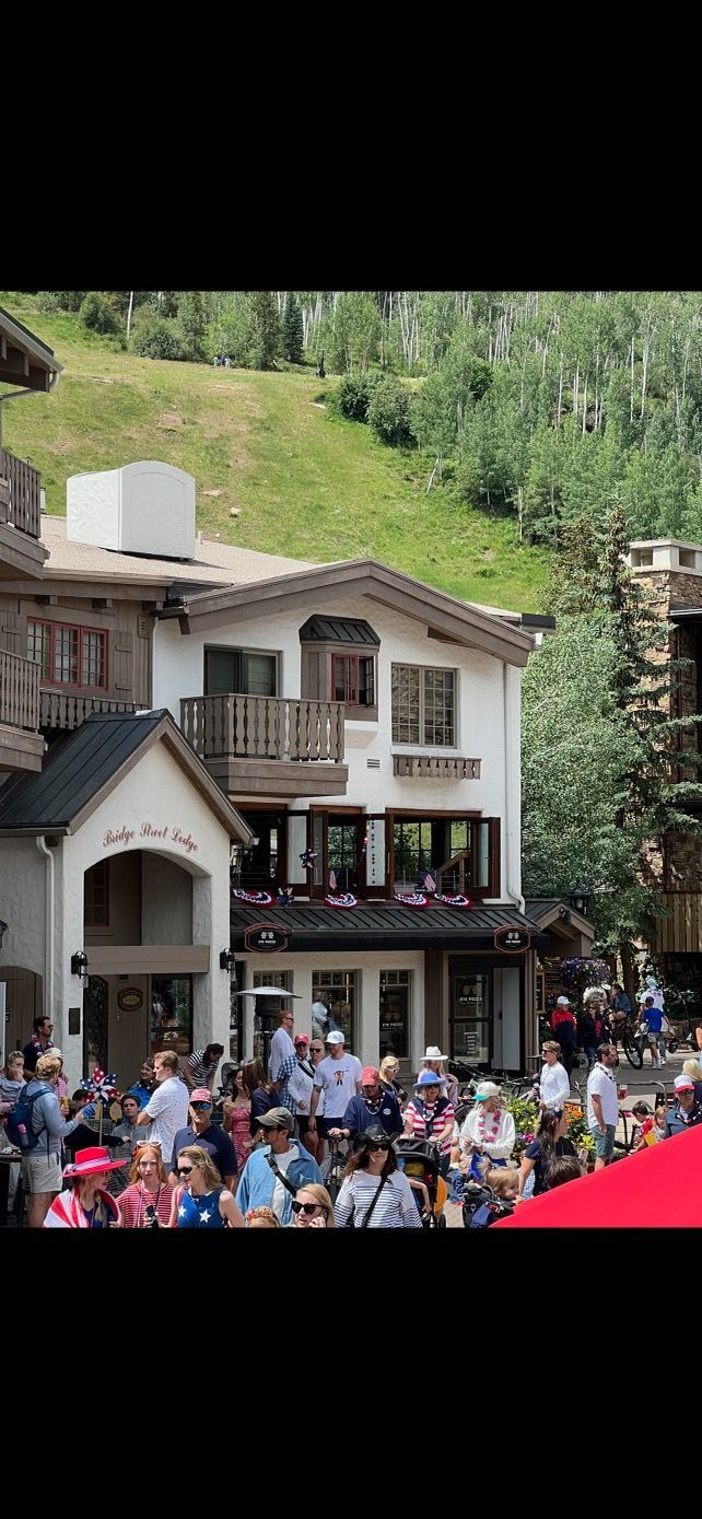 People gathered in front of a building with a green hill background.