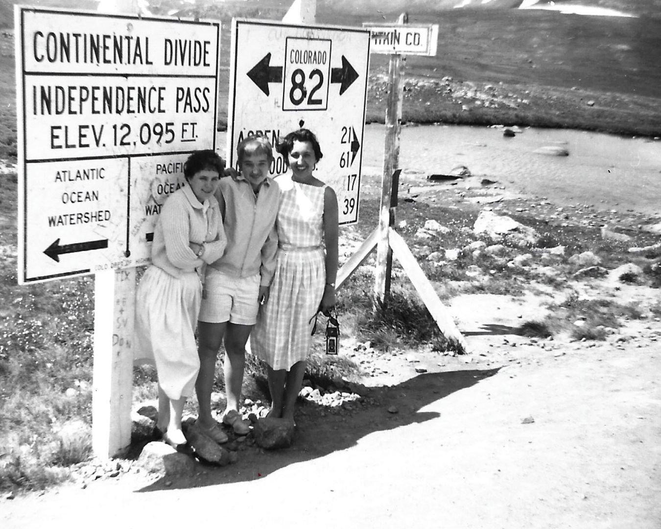 Three people at Independence Pass, Colorado, near a sign. It marks the Continental Divide at 12,095 feet.