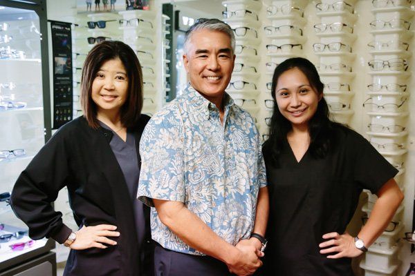 A man and two women pose for a picture in an optical shop
