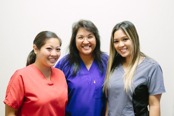 Three nurses are posing for a picture together and smiling.