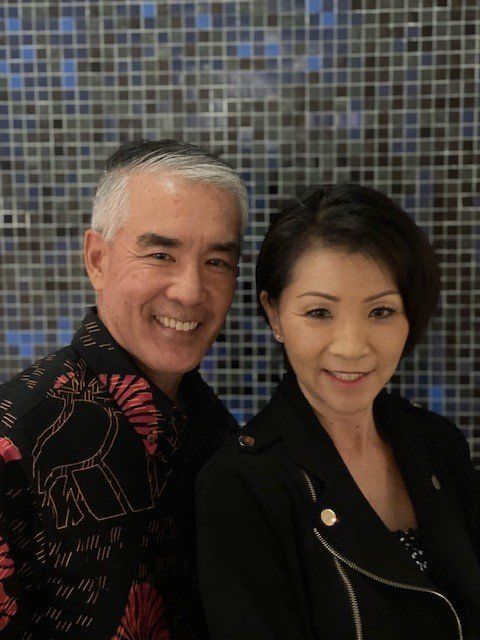 A man and a woman are posing for a picture in front of a mosaic wall.