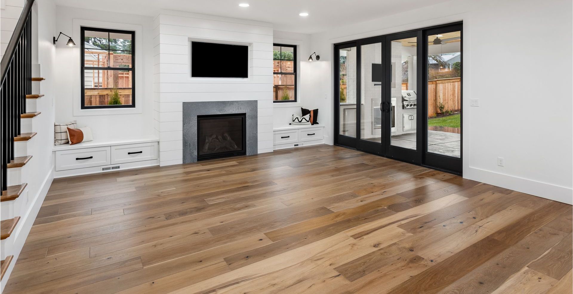 A living room with hardwood floors , a fireplace and a flat screen tv.