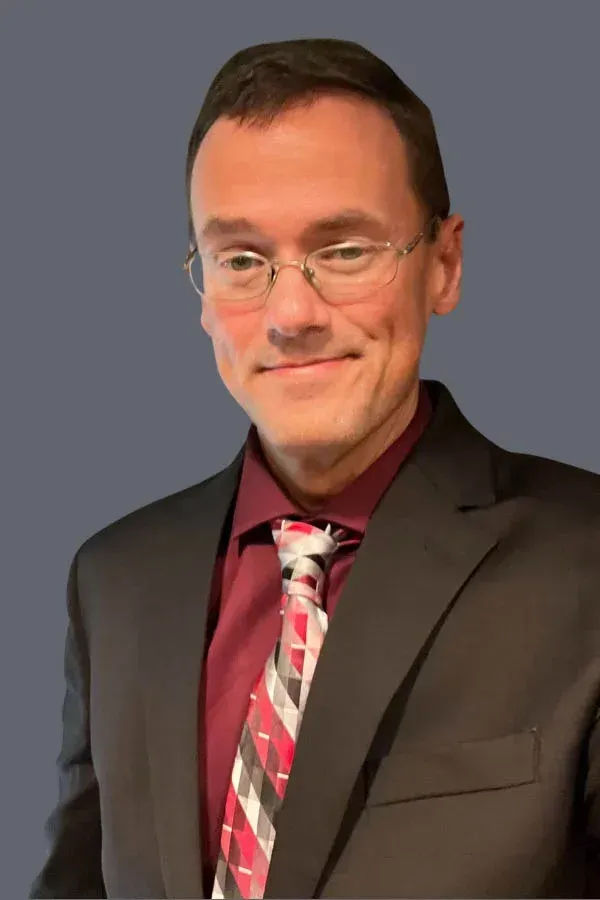 A man in a suit and tie is smiling for the camera.