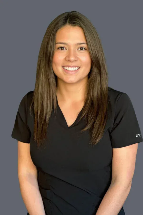 A woman in a black scrub top is smiling for the camera.