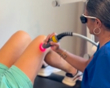 technician performing laser therapy on a female patient