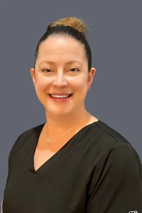 A woman in a black scrub top is smiling for the camera.