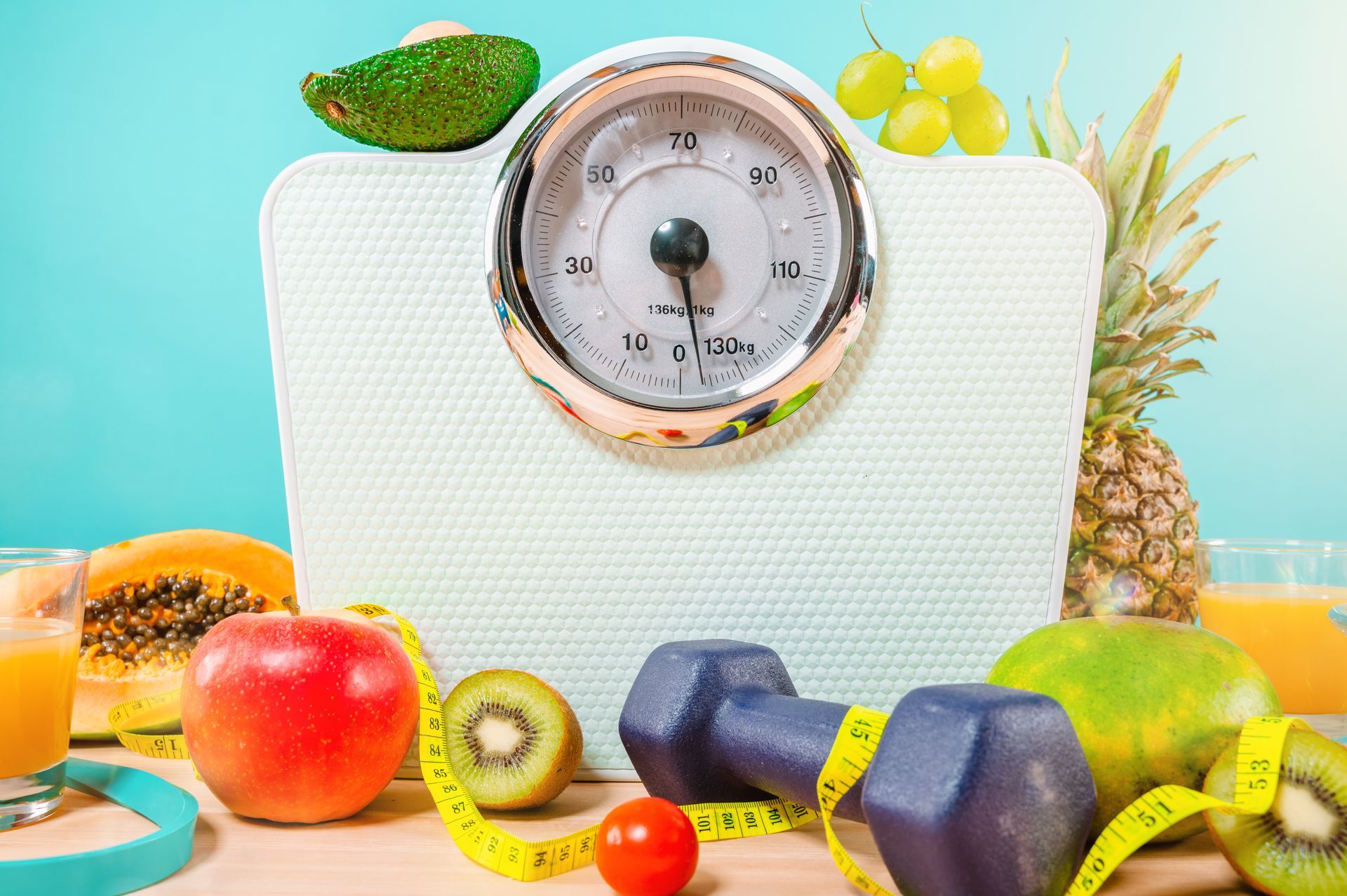 a scale in front of a blue background with fruits and a weight in front