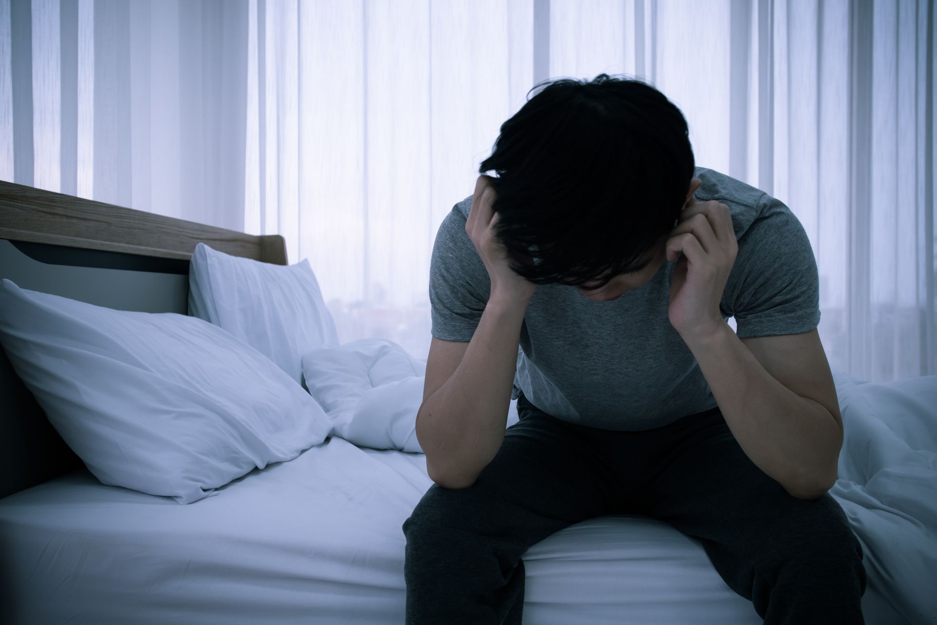 man sitting on bed in pain