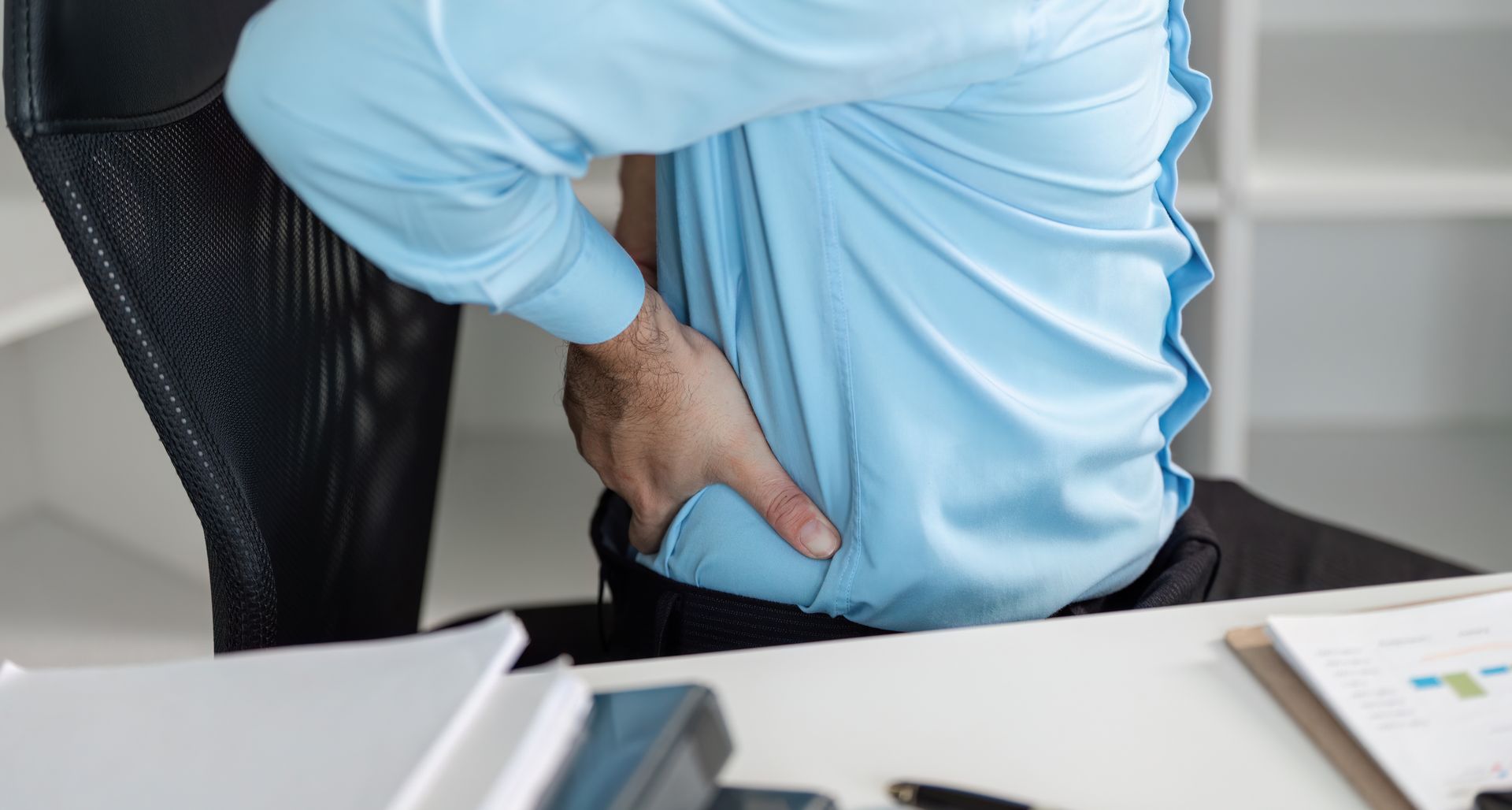 an employee rubbing his lower back in pain