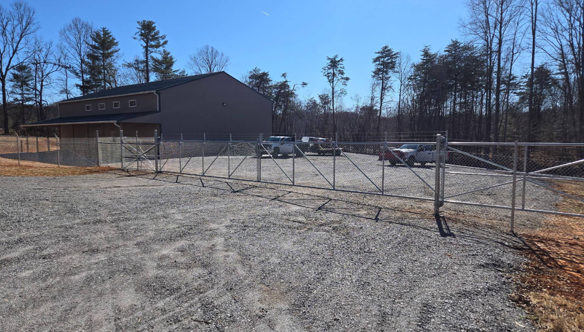 Large chain-link commercial fence with wide gate installed by a Boones Mill commercial fence contractor, securing a business property
