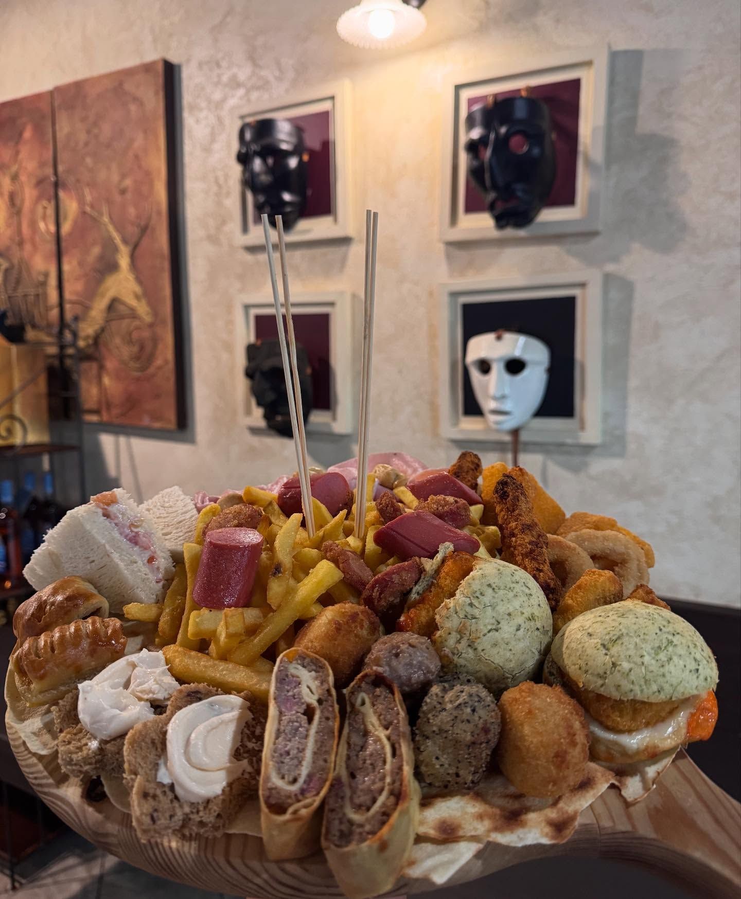 Grande tagliere di legno ricoperto di cibi fritti, snack e antipasti assortiti, in un ambiente da ristorante.