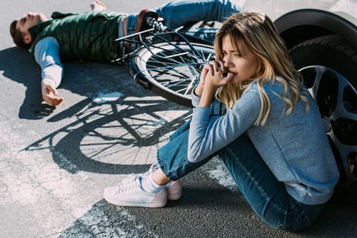 Scared young woman sitting near car after DUI causing death or substantial bodily harm