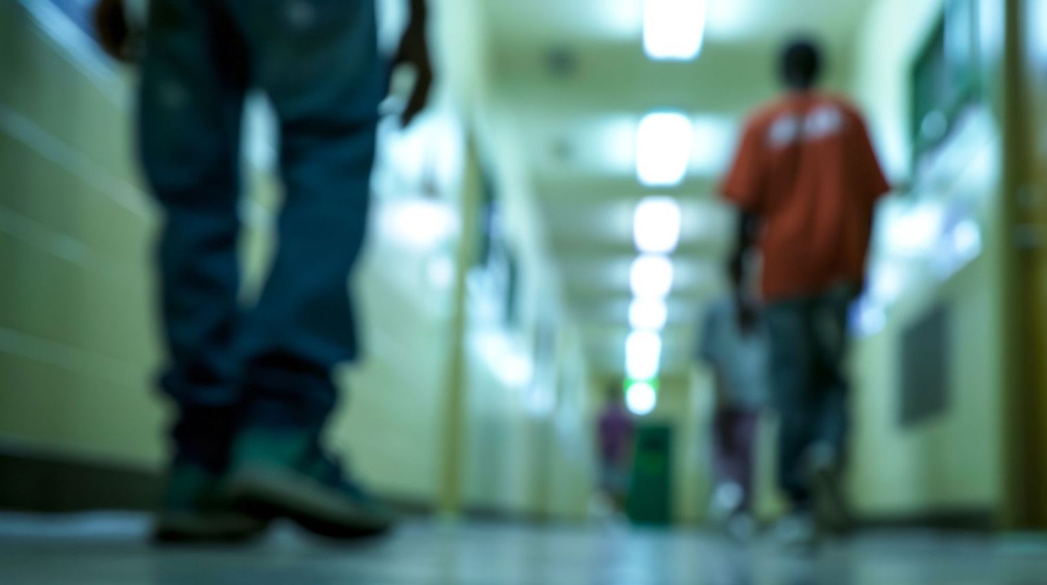 A blurry picture of people walking down a hallway in a jail.