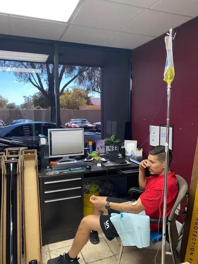 A man is sitting in a chair with an iv in his arm talking on a cell phone.