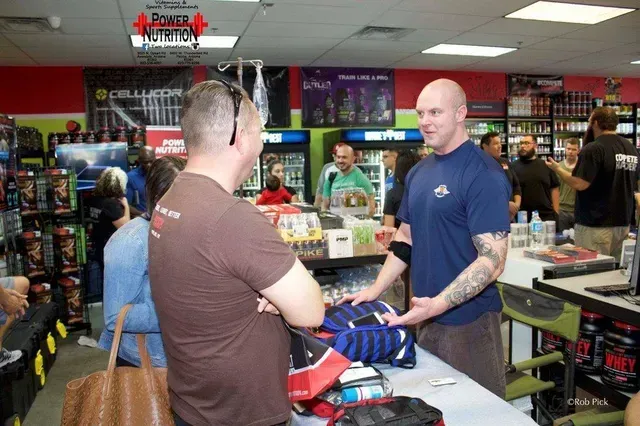 A man in a blue shirt is talking to another man in a store