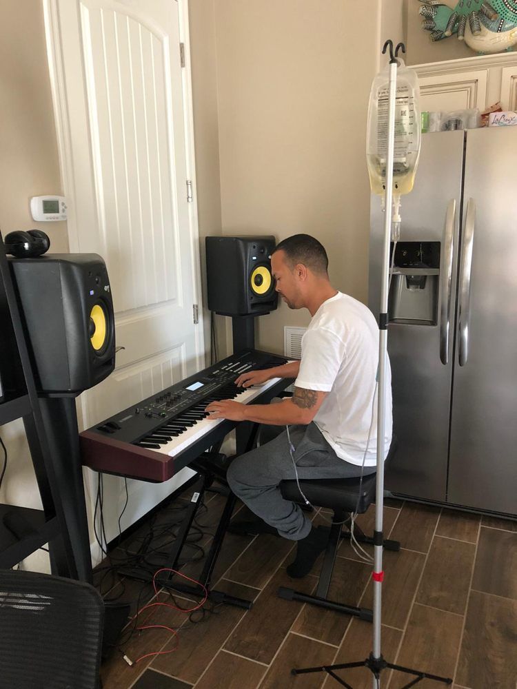 A man is sitting in a chair playing a piano in a kitchen.