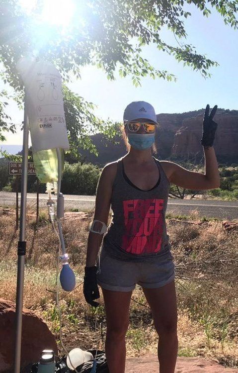 A woman wearing a mask and sunglasses is giving a peace sign.