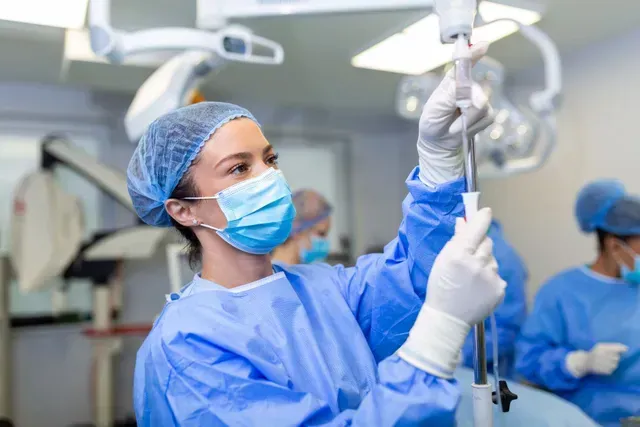 A female surgeon is preparing an injection in an operating room.