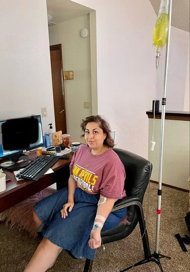 A woman is sitting in a chair with an iv in her arm.
