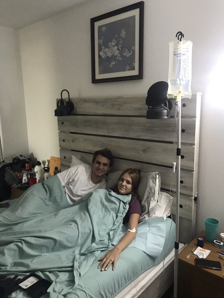 A man and a woman are laying in a bed with an iv bag.