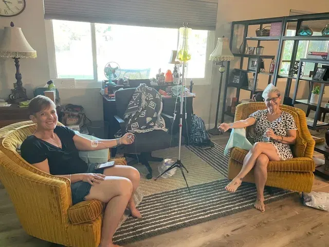 Two women are sitting in chairs in a living room.