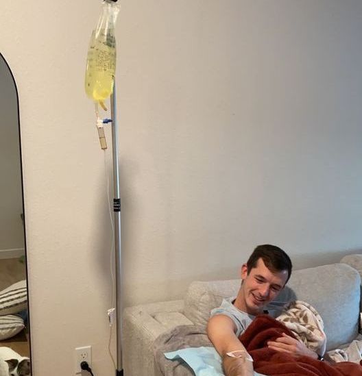 A man is laying on a couch with an iv in his arm.