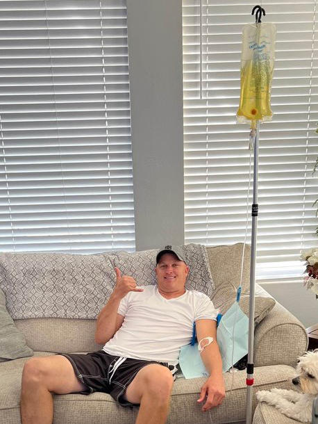 A man is sitting on a couch with an iv in his arm.