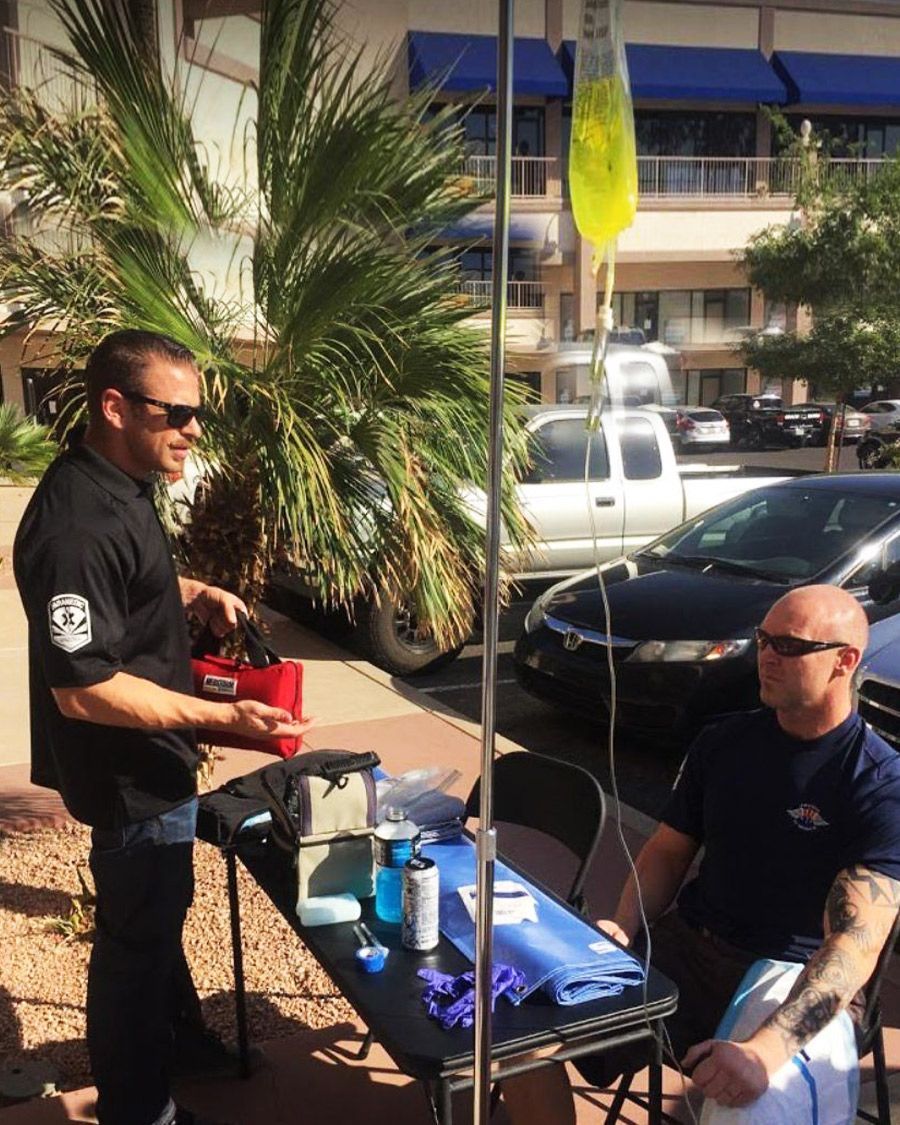On-site or event mobile IV hydration service setup, showing a professional and a client receiving treatment outside in a sunny location.