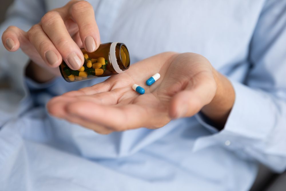 A woman is pouring pills from a bottle into her hand.