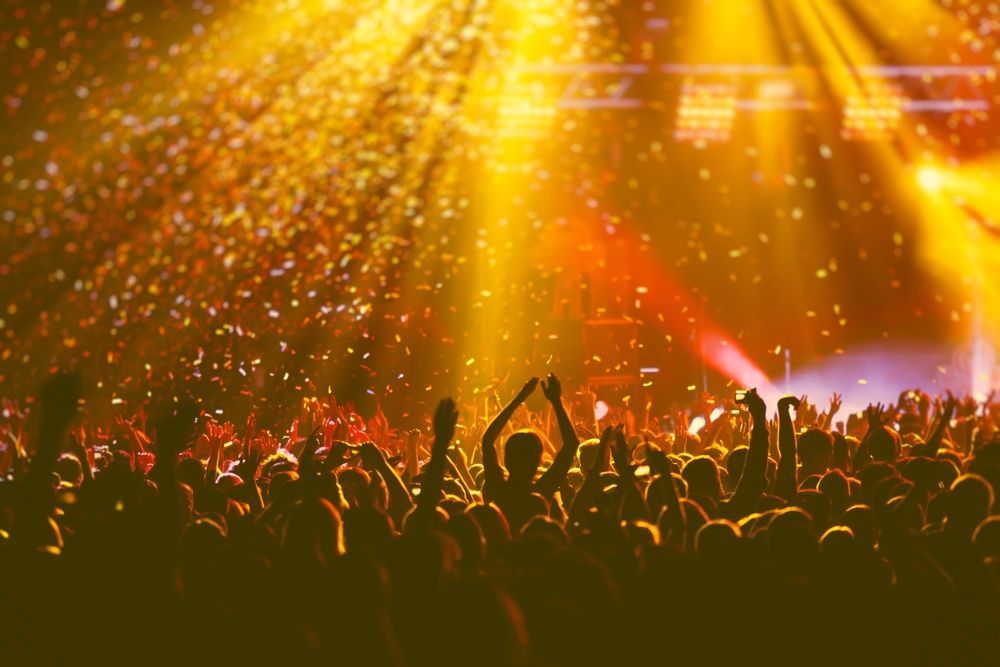 A crowd of people are standing in front of a stage at a concert.
