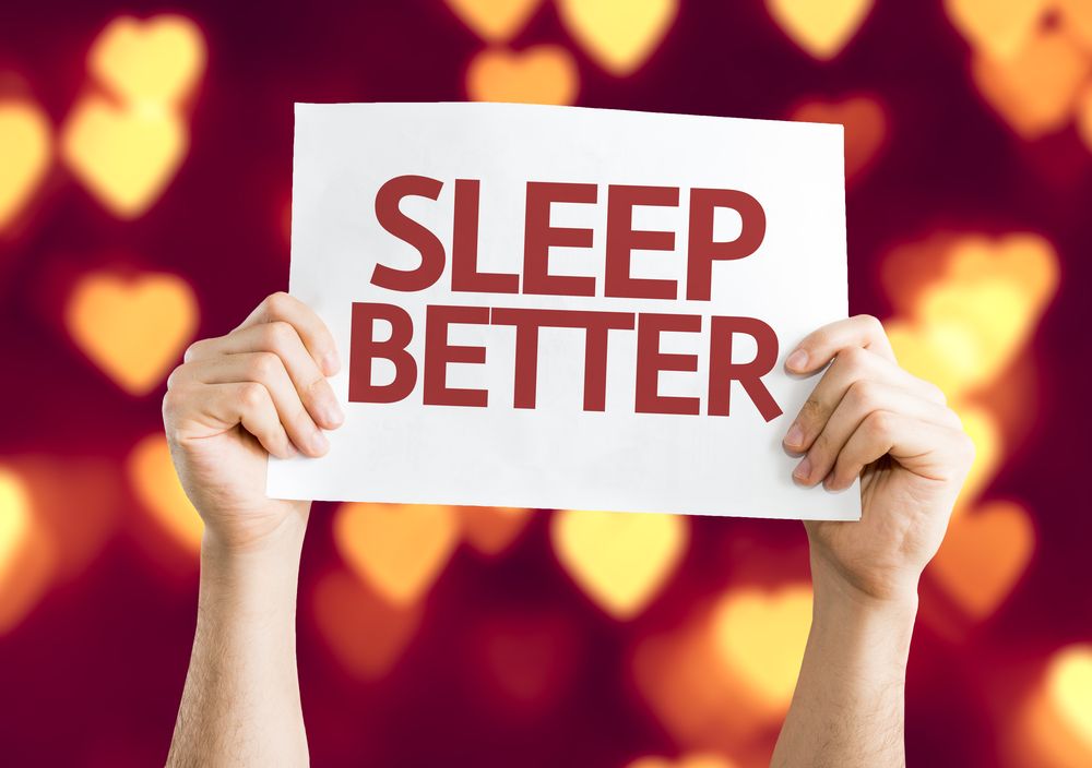 A person is holding a sign that says sleep better.